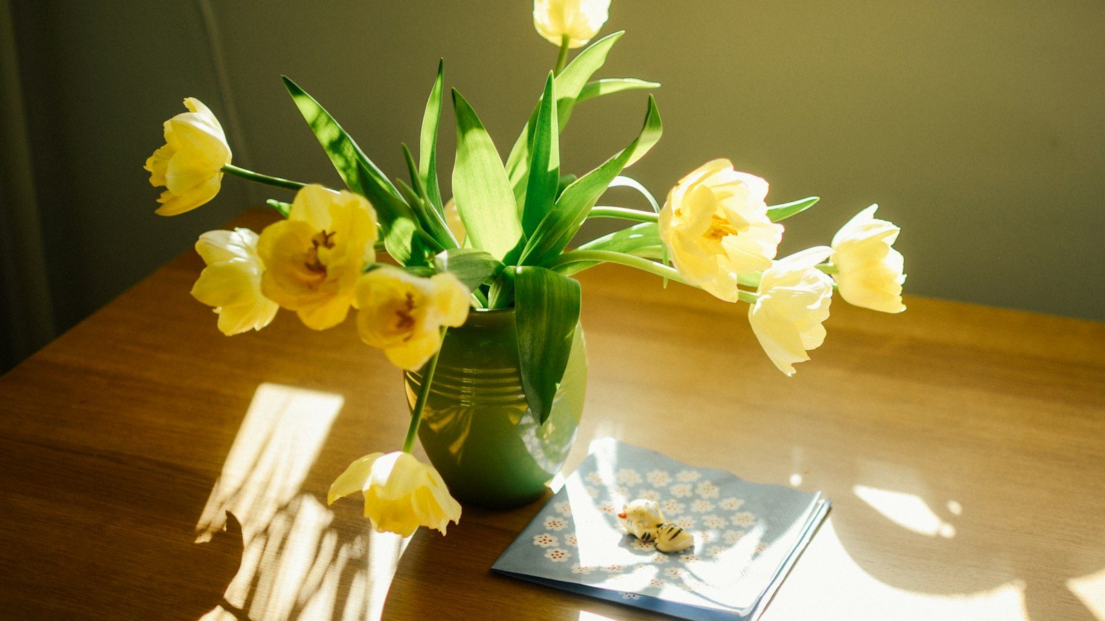Yellow tulips in a vase on a sunlit table