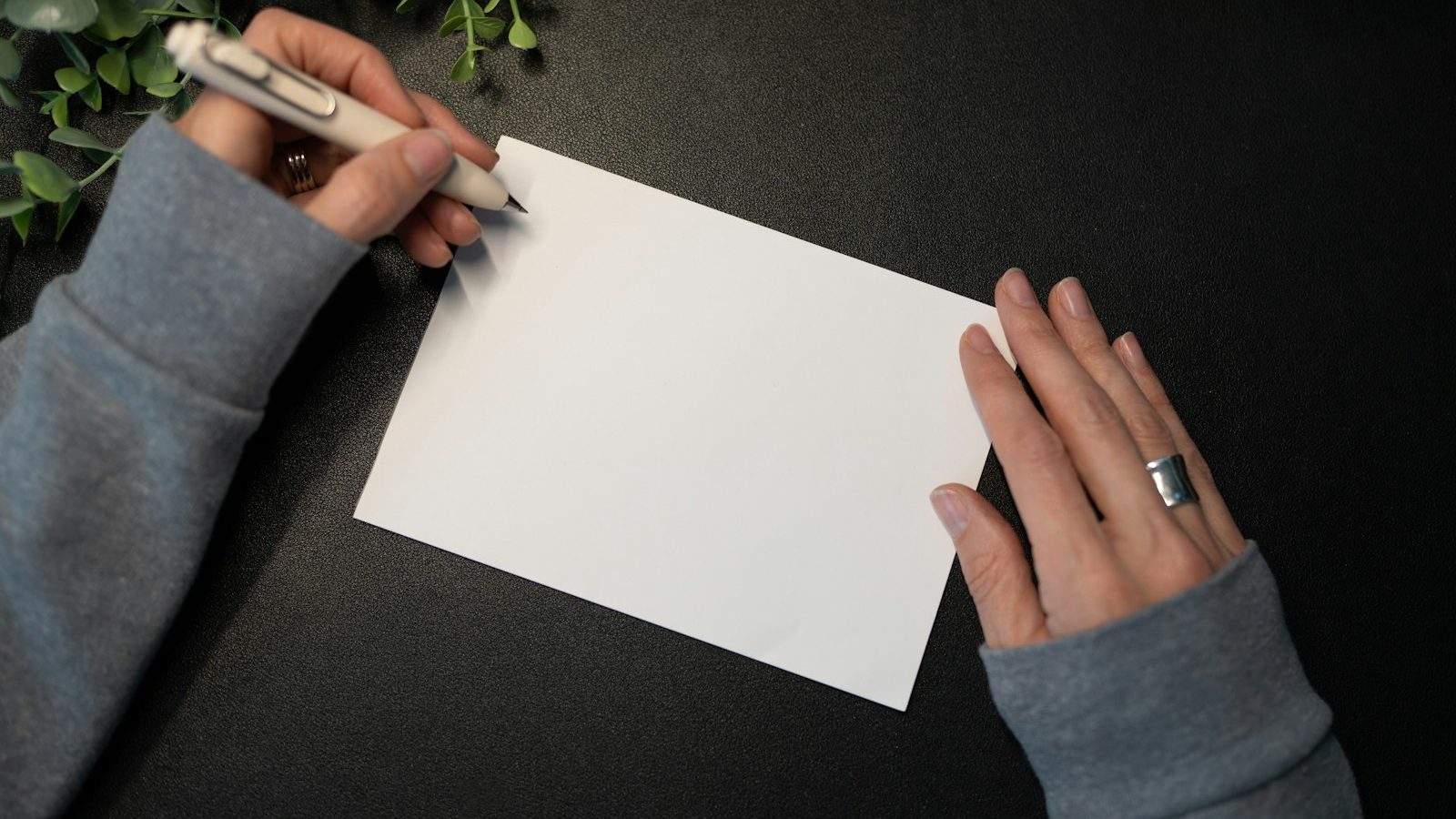 Hands writing a message inside a blank greeting card