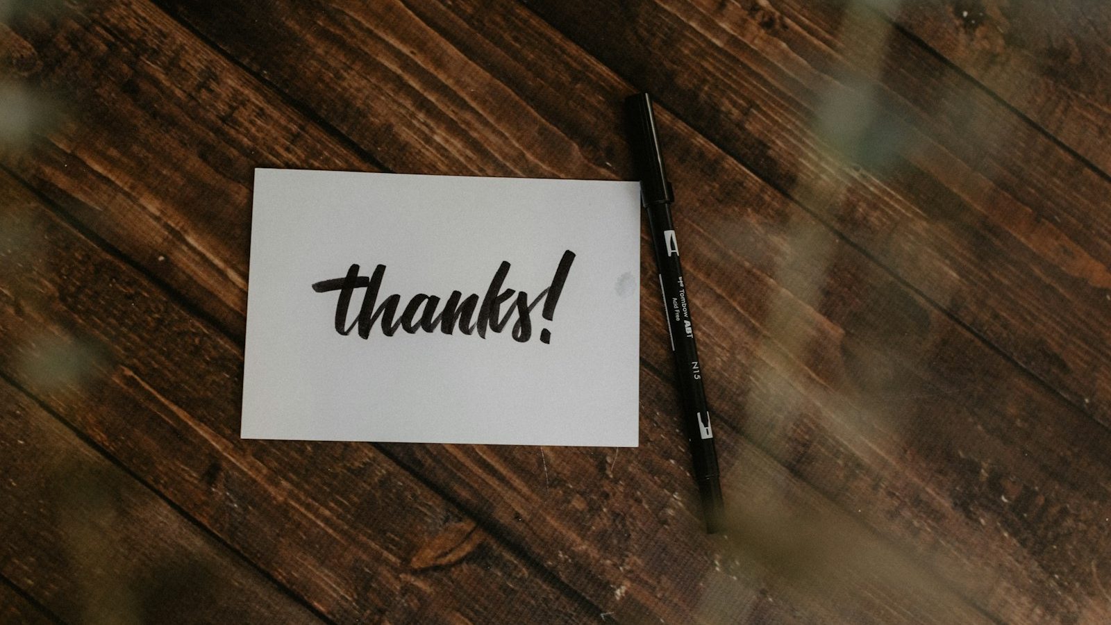 Handwritten thanks note and pen on a wooden table